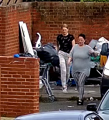 Two females walking away from pile of rubbish